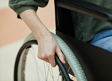 A close-up of a hand in a yellow rubber glove scrubbing a golden bathroom faucet with a foamy sponge near a white sink and tiled wall.
