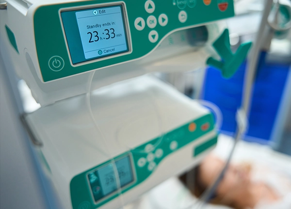 A man from behind is using a squeegee to clean a large glass pane or barrier, likely outdoors or on a patio, with a potted plant in the foreground.
